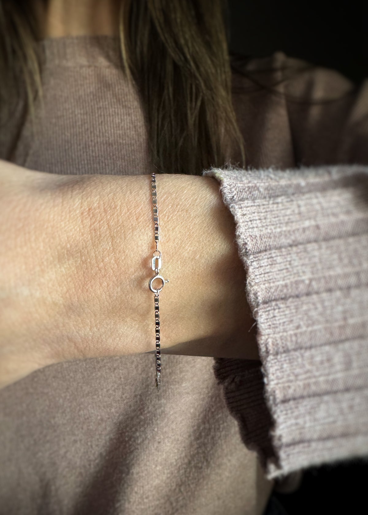 14k white gold fine mirror chain bracelet on a wrist with a neutral background