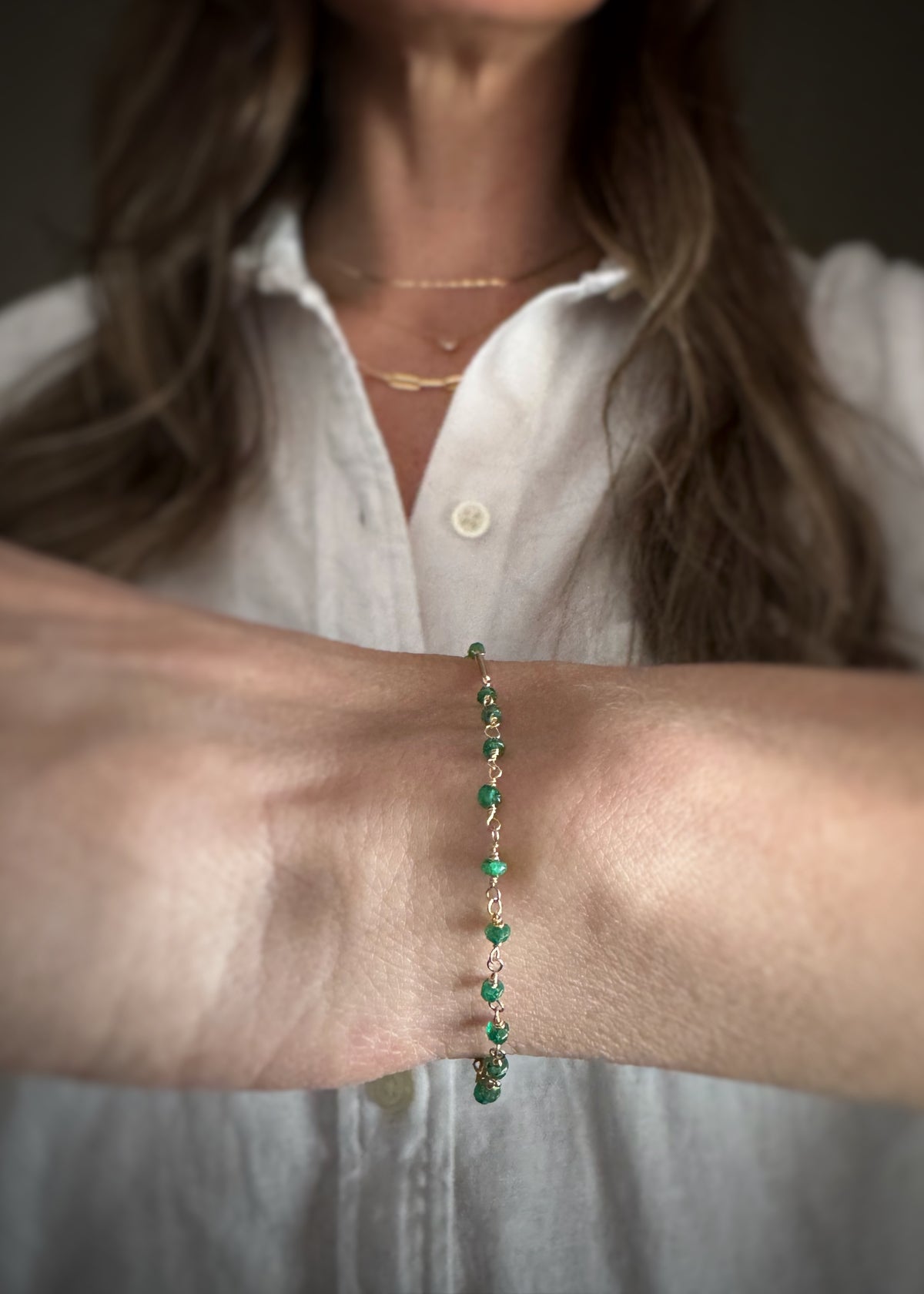 side view and close-up of a person wearing a kelly green emerald bead chain bracelet on a neutral background