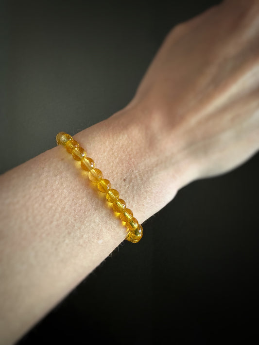 golden yellow citrine beaded bracelet on a wrist against a dark background