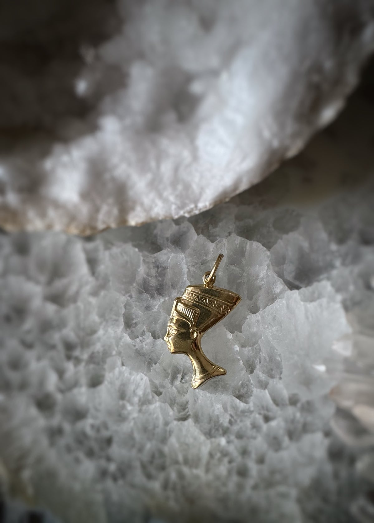 hollow 14k yellow gold 3D pendant shaped like Queen Nefertiti on a textured white surface