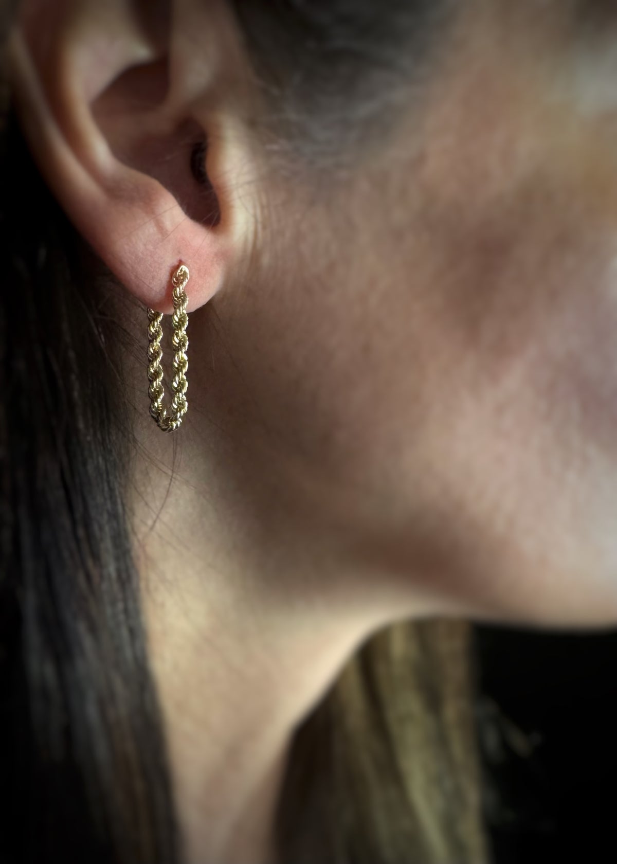 Close-up of a 14k yellow gold chain earring that is a hoop worn on an ear.