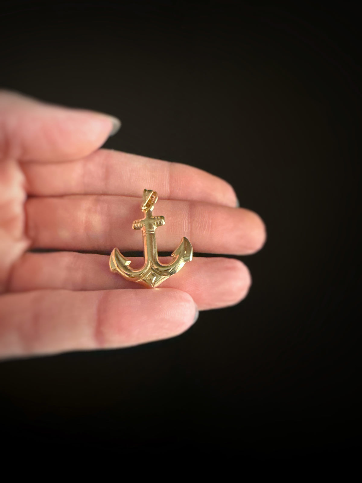 Estate 14k yellow gold large 3D anchor pendant held in a hand against a black background