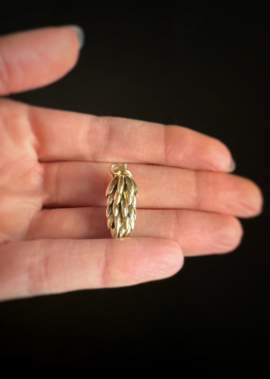 Estate 14k yellow gold large 3D bunch of bananas charm held in a hand against a black background