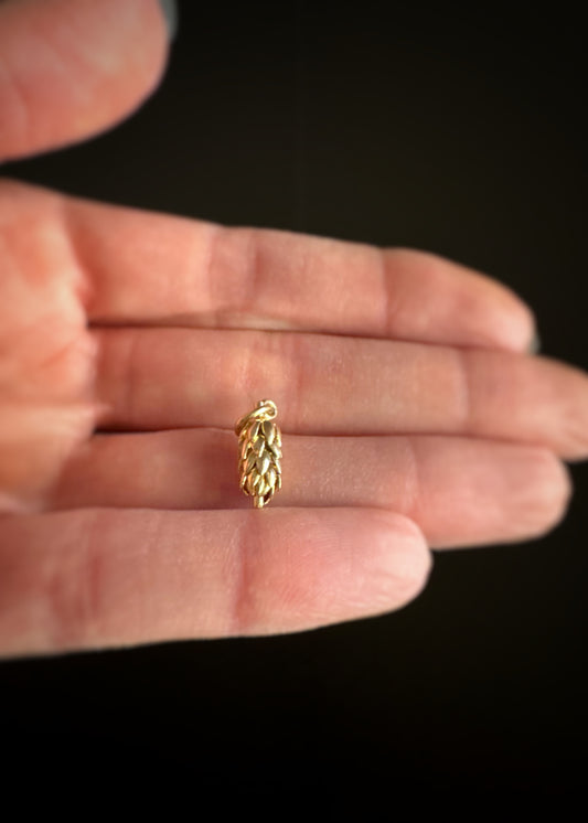 Gold banana bunch charm held in a hand against a dark background