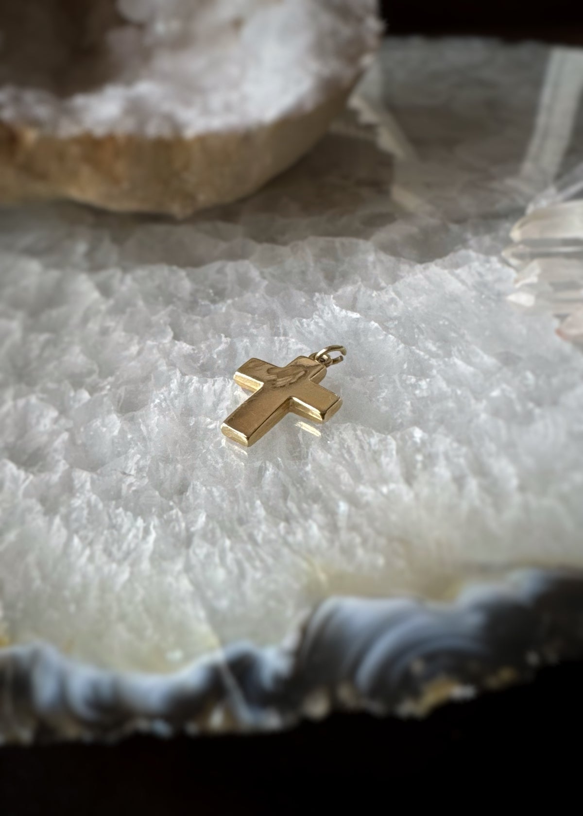 back and side view of and estate 14k yellow gold 3d textured cross charm pendant on a textured white surface