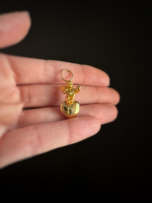 Estate 14k yellow gold charm with a heart and angel figure on top holding a mandolin instrument against a black background