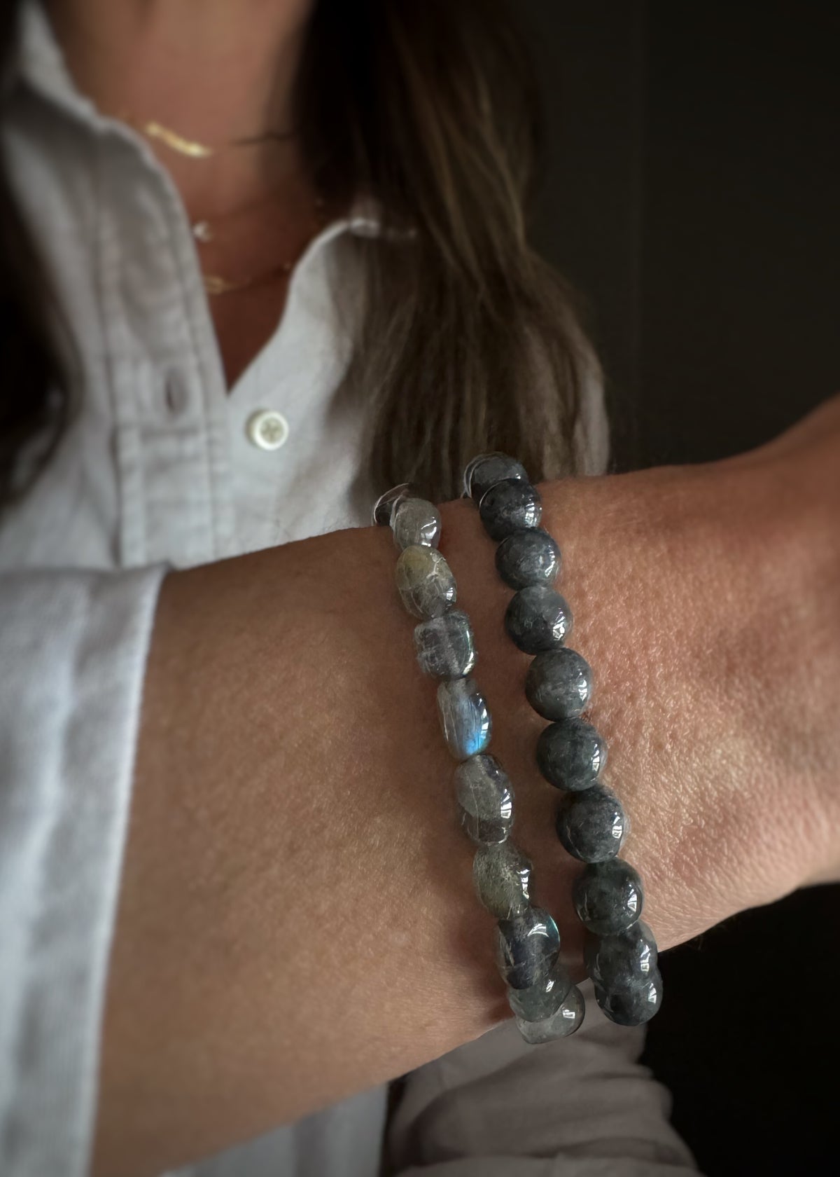 Close-up of a person wearing two different shape beaded labradorite bracelets on their wrist.