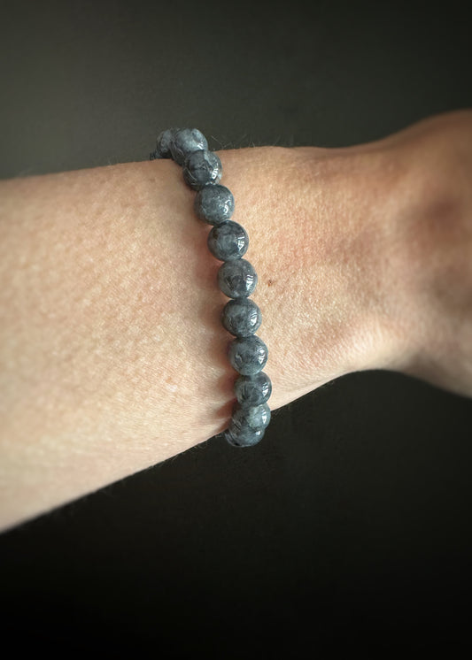 Grayish blue round labradorite beaded elastic stretch bracelet on a wrist against a dark background