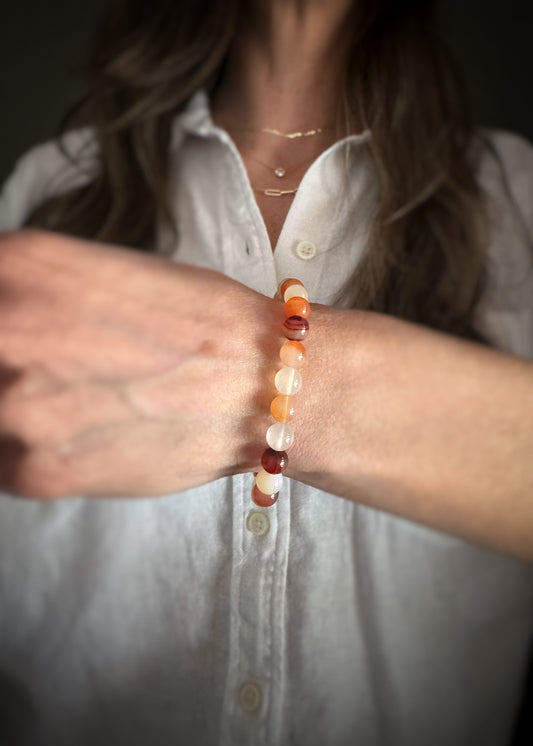 Person wearing a carnelian beaded stretch bracelet on a blurred background