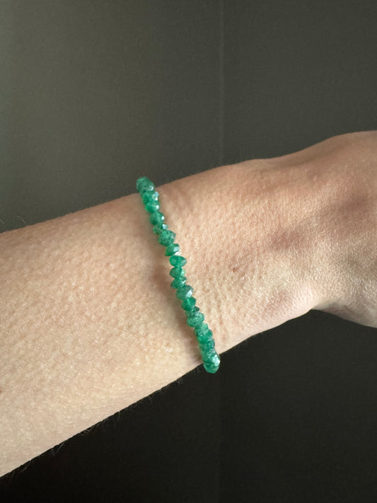 green faceted quartz beads strung on stretchy cord bracelet on a wrist against a dark background