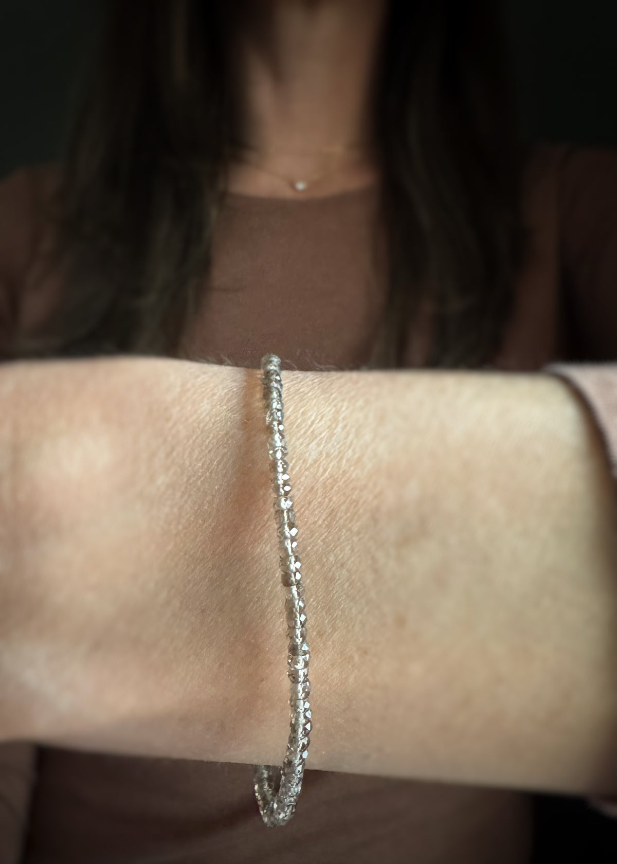beaded bracelet of faceted smoky quartz beads on a wrist with a blurred background