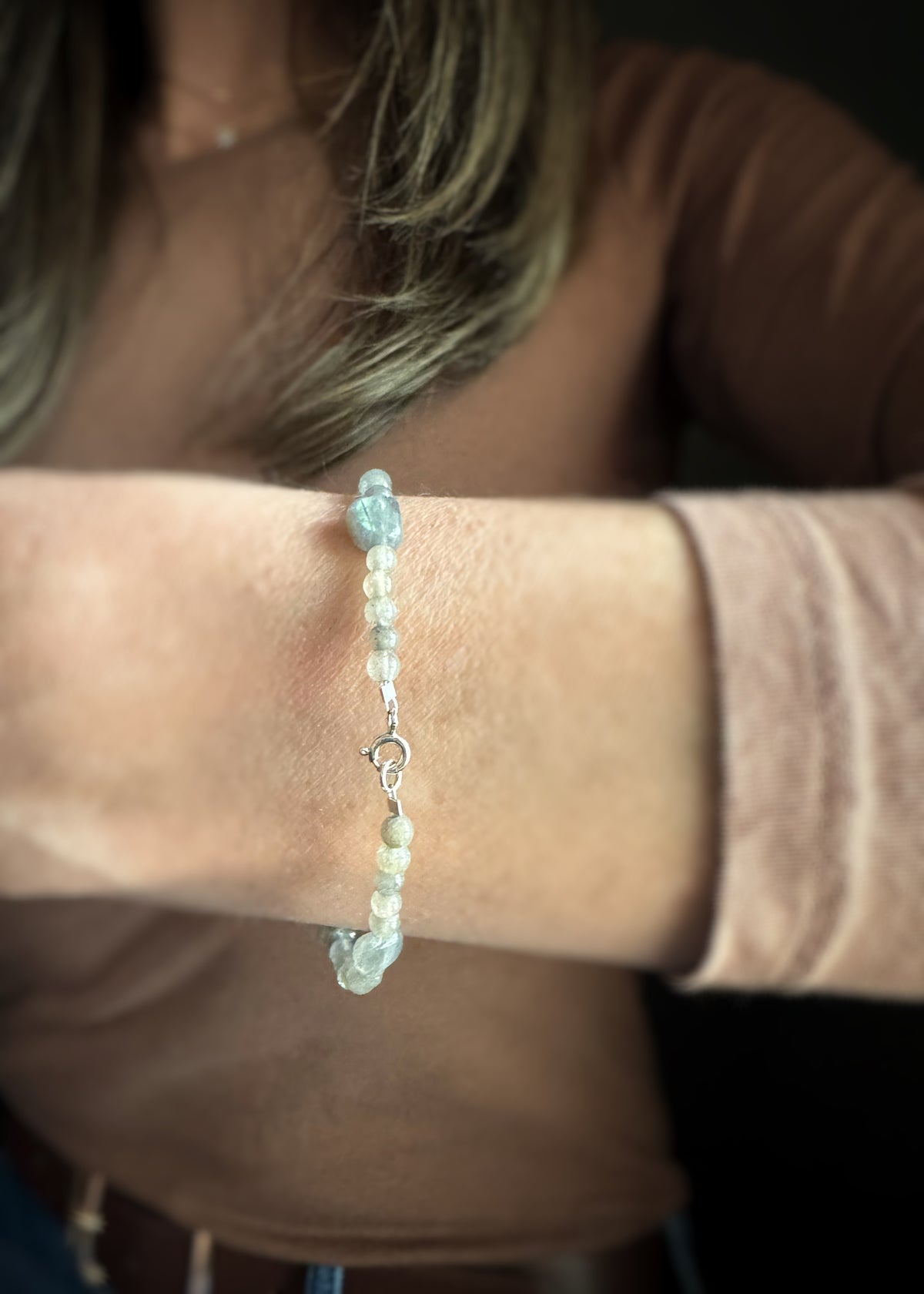 Close-up of a wrist wearing a gray and blue labradorite bead bracelet showing the spring ring clasp for closure